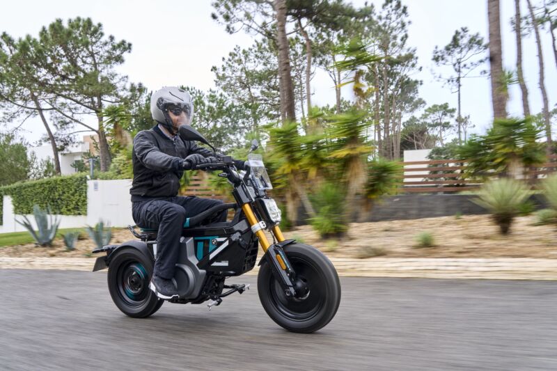 A man rides a small electric scooter in the rain