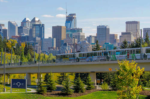 A Calgary Ctrain crossing a bridge during the afternoon in summer.