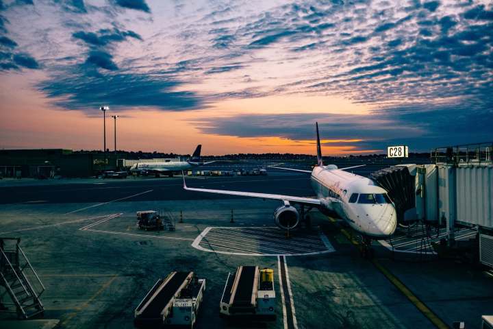 Aircraft parked on airport tarmac with sunset in the background.