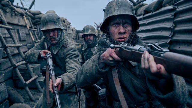 Three soldiers holding up guns in a murky trench