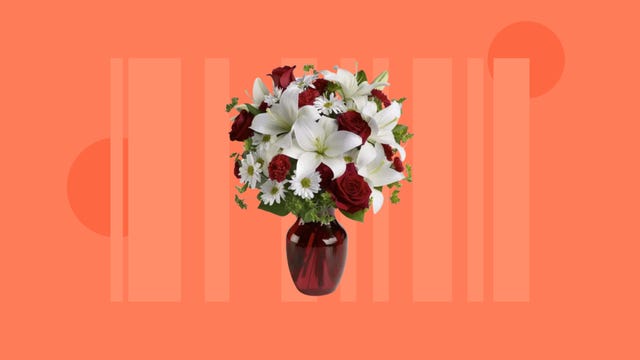 A bouquet of white and red flowers in a red vase is displayed against an orange background.