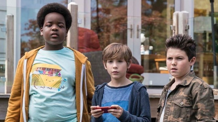 Three young boys stand next to each other and stare.