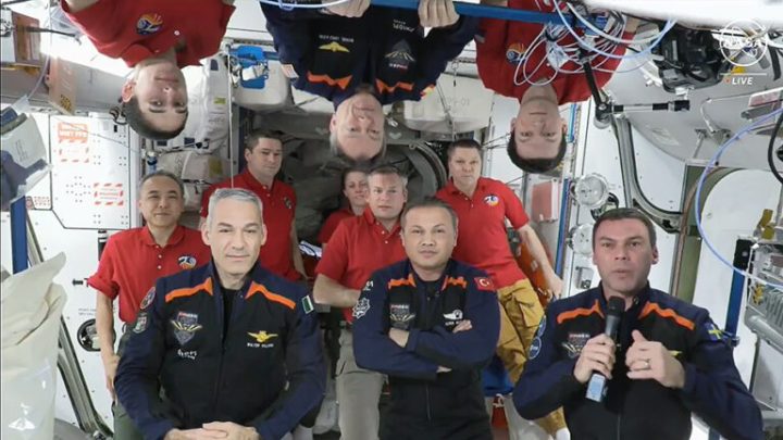 The 11 crew members representing the Expedition 70 (red shirts) and Axiom Space 3 (dark blue suits) crews gather for a farewell ceremony calling down to mission controllers on Earth. 