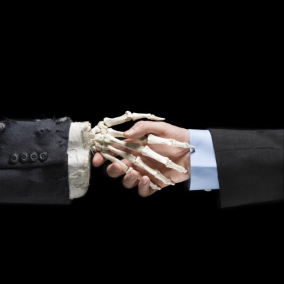 Businessman shaking hands with skeleton