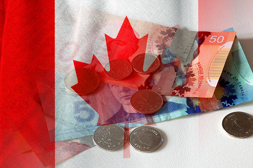 Canadian dollar cash bills and coins and flag of Canada