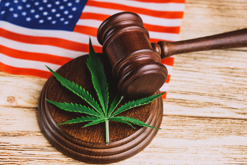 Cannabis leaf on sound block under gavel over US flag.