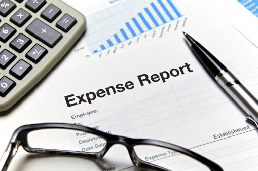 Close-up of an expense report with glasses and a calculator