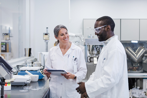 Female lab director smiles as male colleague reports experiment results