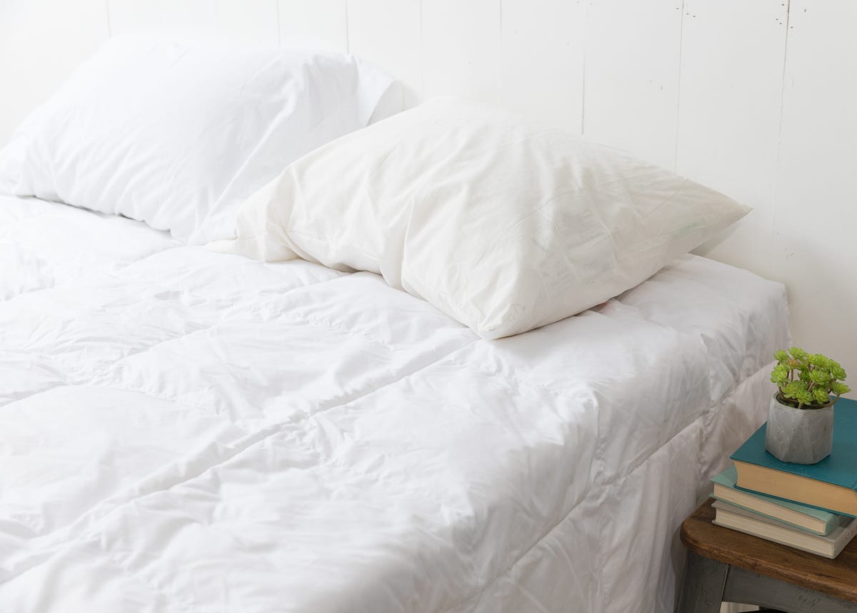 two pillows inside white pillow cases on top of a bed covered with a white comforter.