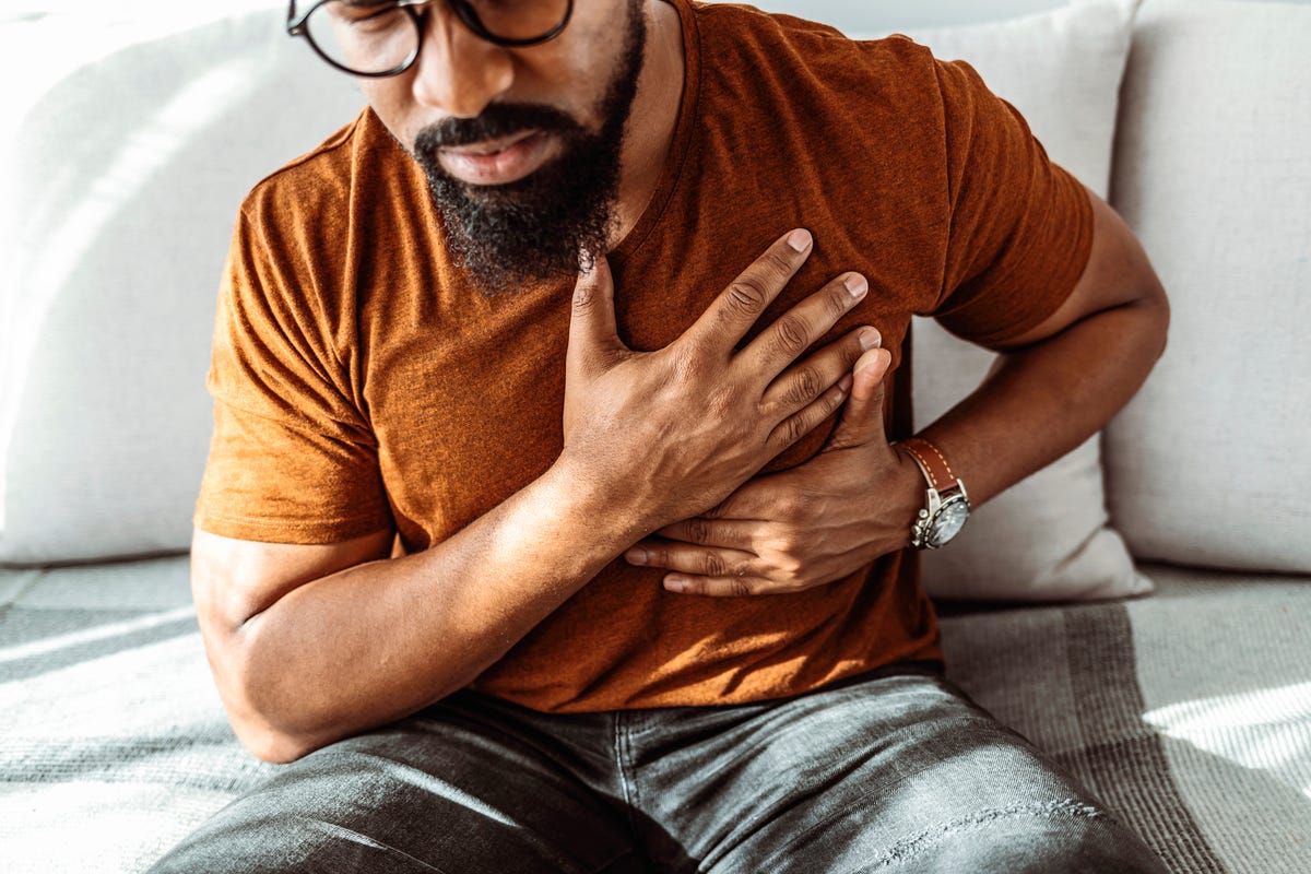 A man with a beard with his hands over his heart