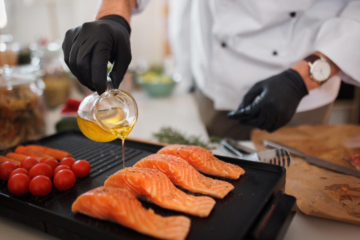 Someone pouring oil over salmon filets