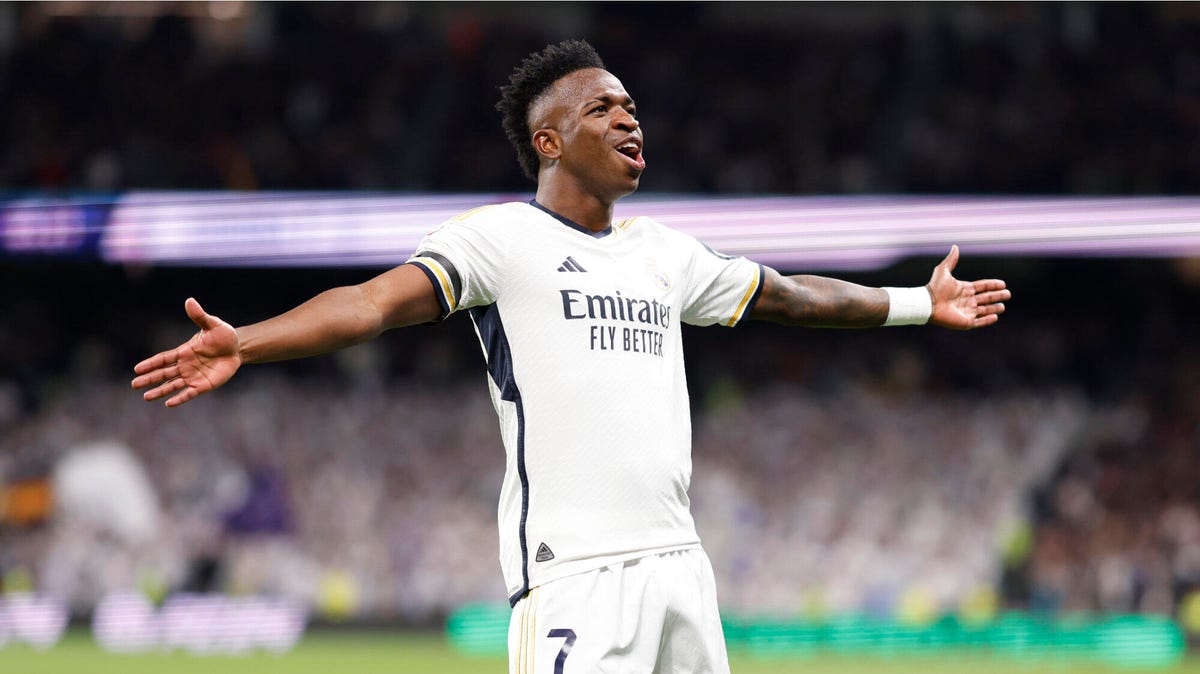 Real Madrid forward Vinicius Jr. celebrating with his arms outstretched.