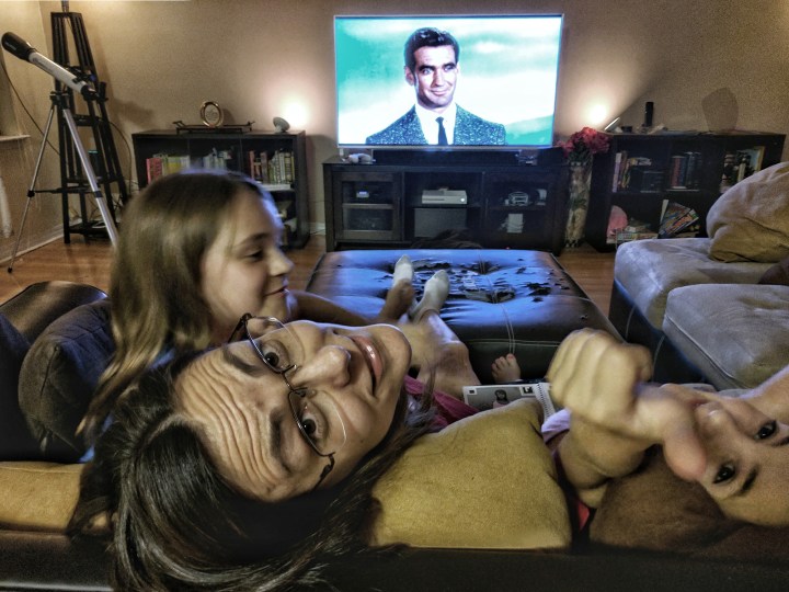 Three young women on a couch watching an old-time movie. Without goggles.