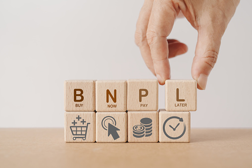 Hand arranged wooden cube blocks with BNPL, alphabets abbreviation , and icon. For buy now pay later online shopping concept