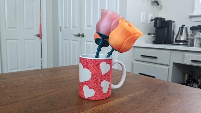 A coffee mug covered in hearts with 3D printed roses in it