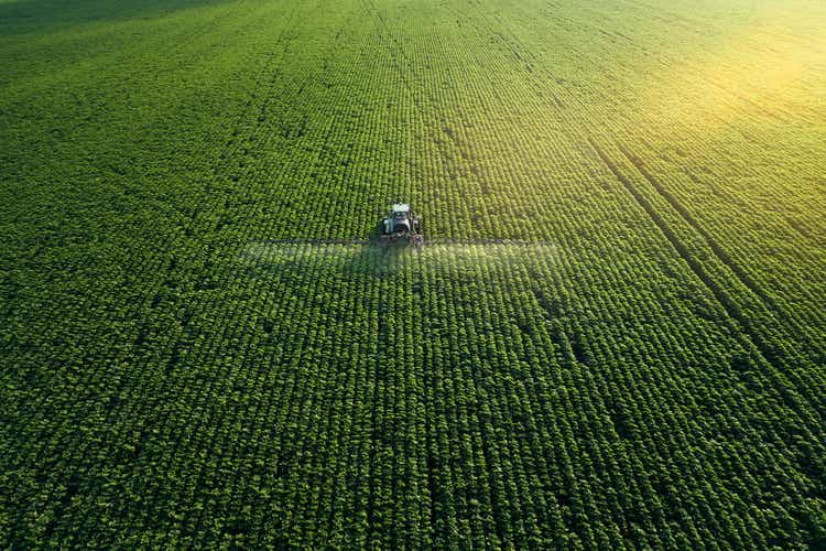 Taking care of the Crop. Aerial view of a Tractor fertilizing a cultivated agricultural field.