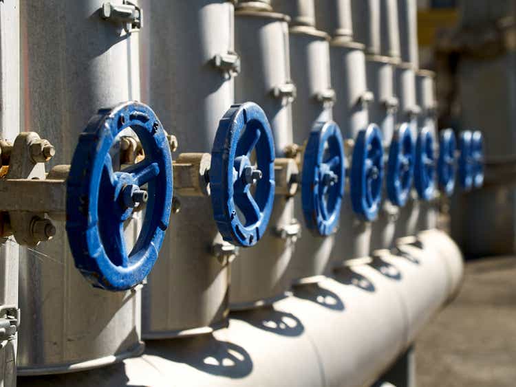 Phantom Blue industrial valves in a row on petrochemical plant pipelines system selective focus over out of focus background.