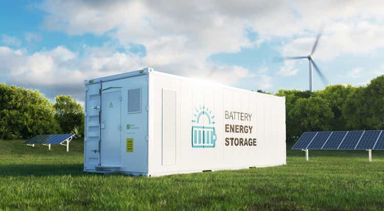 concept of a modern high-capacity battery energy storage system in a container located in the middle of a lush meadow with a forest in the background. 3d rendering