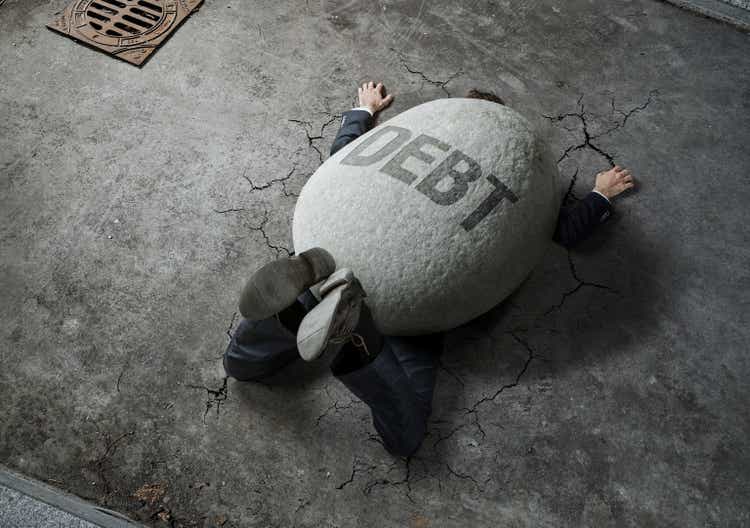 Trouble, debt, crisis concept, high angle view of businessman crushed by the huge stone