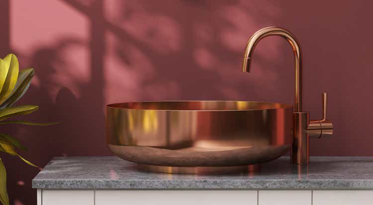 Modern and luxury marble bathroom vanity counter top with brass round washbasin in sunlight and leaf shadow from window on red maroon wall background