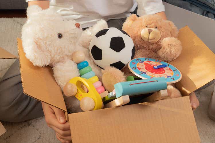 Teenager sorting and collect kid toys, clothes into boxes at home. Donations for charity, help low income families, declutter home, sell online, moving into new home, recycling, sustainable living