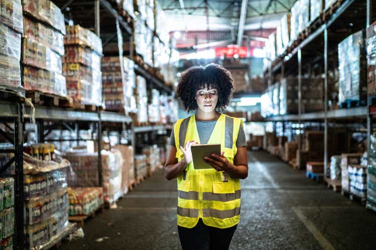 Young woman using the digital tablet in a warehouse