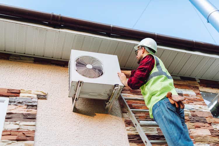 Technician in uniform repairing heat pump