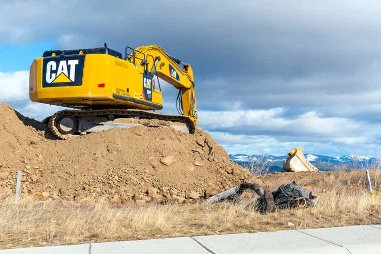 Vista generale di una pala idraulica da miniera CAT 336F Sand in cima a un monte di terra su una collina con montagne innevate in lontananza, a Spokane, Washington.