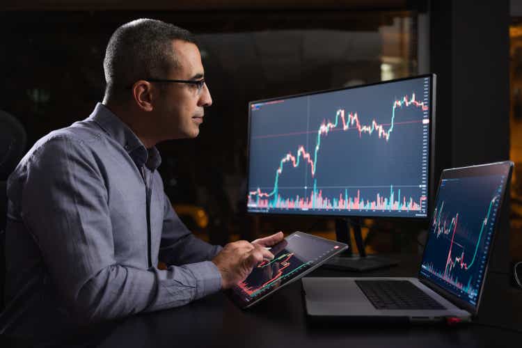 Man Checking His Stock Market Exchange Investment Using His Laptop Computer At Night.