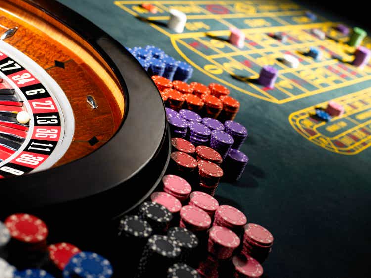 Gambling chips stacked around roulette wheel on gaming table