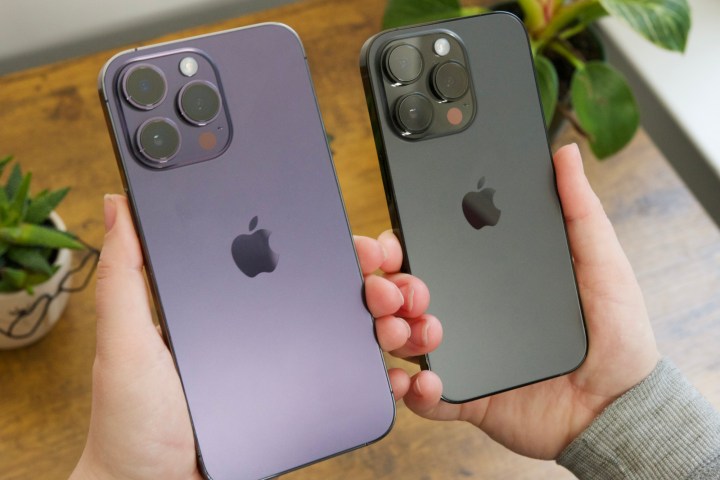 Someone holding an iPhone 14 Pro Max and iPhone 14 Pro next to each other.