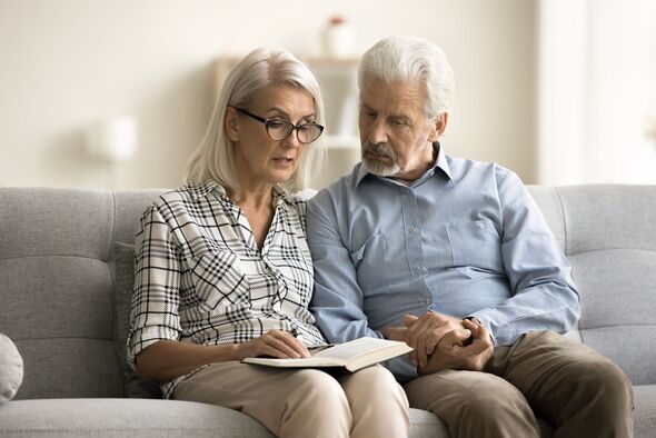 Caring senior wife reading book aloud to older husband