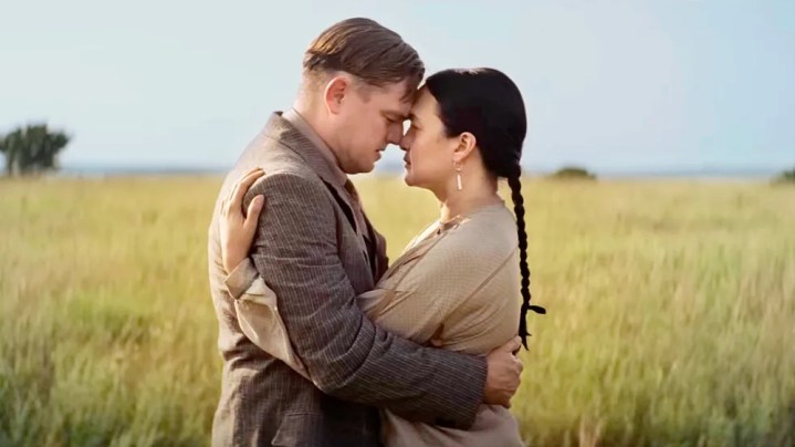 A man and a woman kiss in a field in Killers of the Flower Moon.