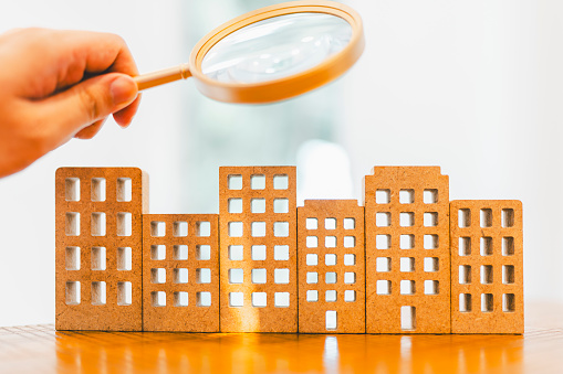 Magnifying glass and house model, house selection, real estate concept.