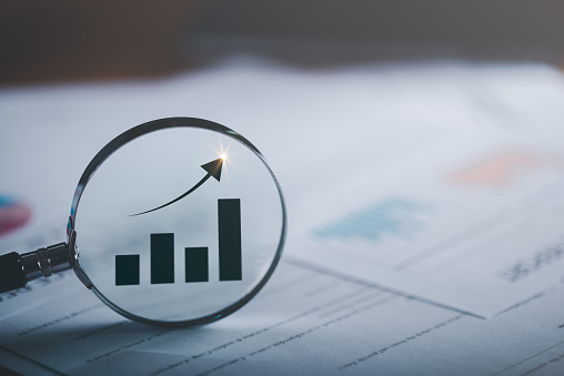 Magnifying glass showing business growth graph ,concept of progress in development, financial efficiency and investment with business strategy for goals and opportunities in the industry future