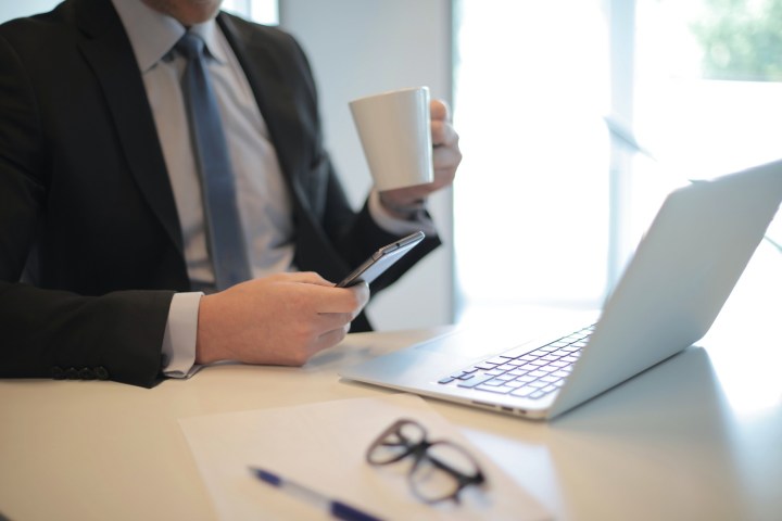 man drinking coffee with laptop and phone