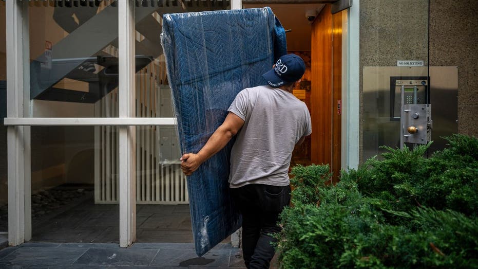 worker moves tv into apartment