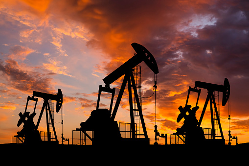 Oil field with rigs and pumps at sunset. World Oil Industry