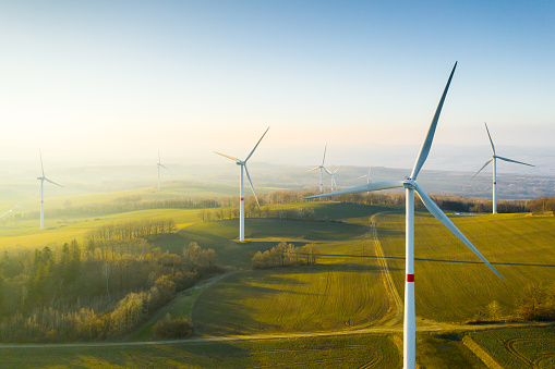 Panoramic view of wind farm or wind park, with high wind turbines for generation electricity with copy space. Green energy concept.