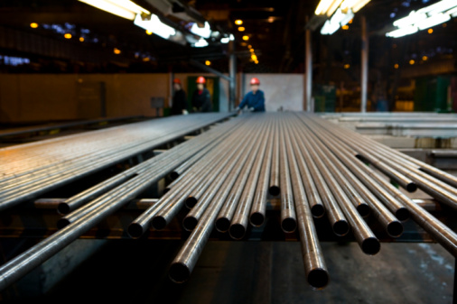 Pipes in row with workers in steel factory