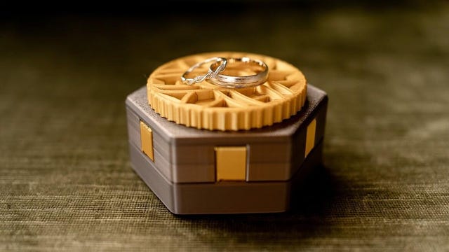 A gold and rose gold 3d printed ring box with 2 rings on top