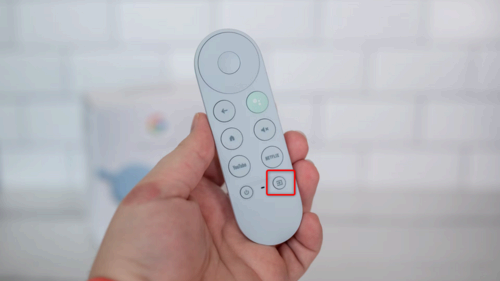 A person holding a Chromecast TV remote.