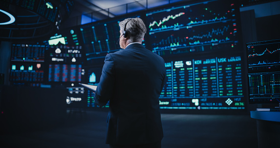 Shot from the Back of a Middle Aged Man Working on the Floor in a Modern Stock Exchange Firm. Specialist Monitoring Companies and Funds, Securities, Derivatives, Investment Products and Bonds