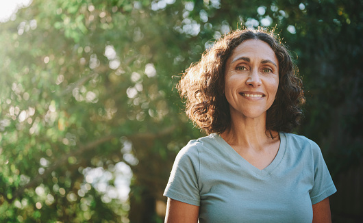 Smiling mature woman standing in a park outdoors in the summertime