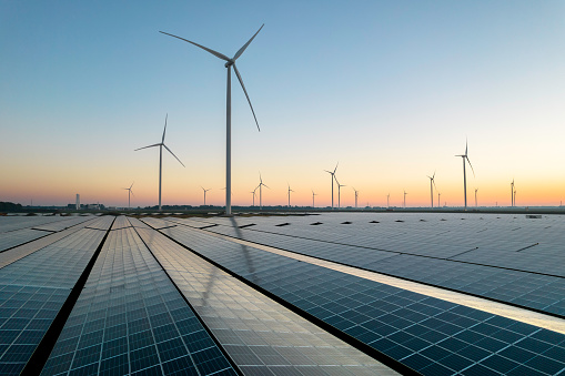 Solar energy field and wind turbines during a summer sunrise