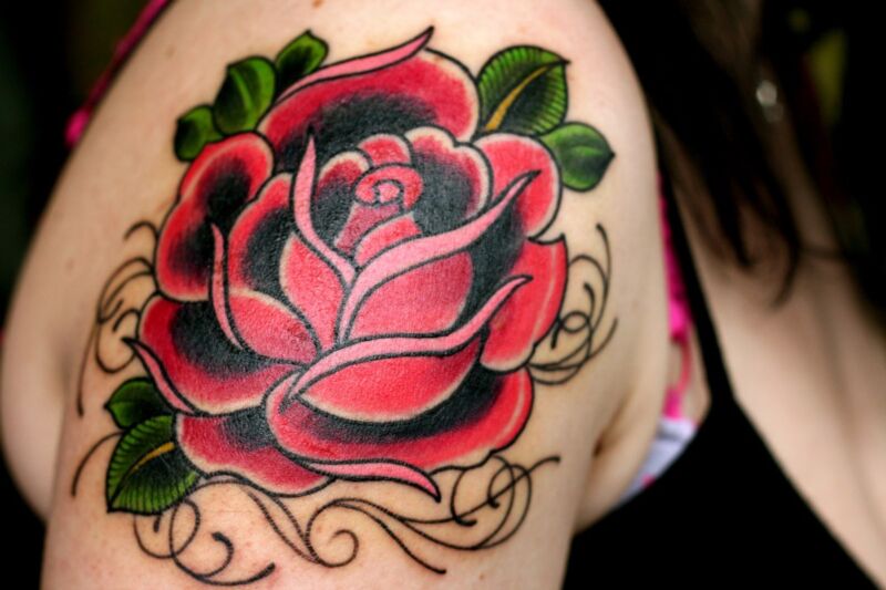 closeup of a rose tattoo on the side of a woman's shoulder