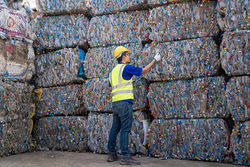 Worker at a recycling collection facility, Employees in a recycling plant inspecting the raw materials in the tablet.