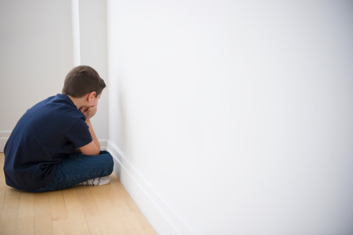 Young boy sulking in corner