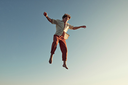 Young man levitating high up with arms outstretched