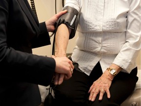 Generic photo of a doctor preparing to check the blood pressure of an elderly patient.